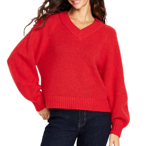 Red V-neck sweater with ribbed cuffs and hem, paired with dark blue jeans.