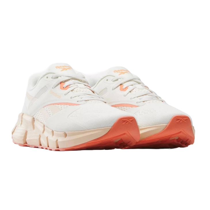 Reebok sneakers in white with peach accents and a chunky sole design.