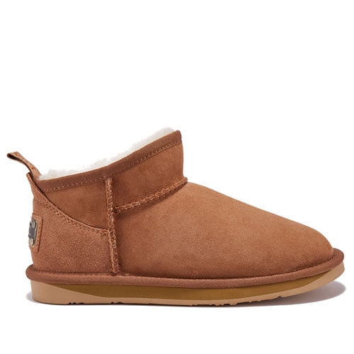These are short, brown sheepskin booties with a plush lining, a flat sole, and a branded tag on the back.
