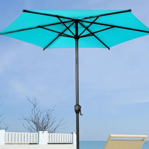 A turquoise patio umbrella with a crank handle, set against a sky backdrop with a glimpse of a sun lounger and white fence.