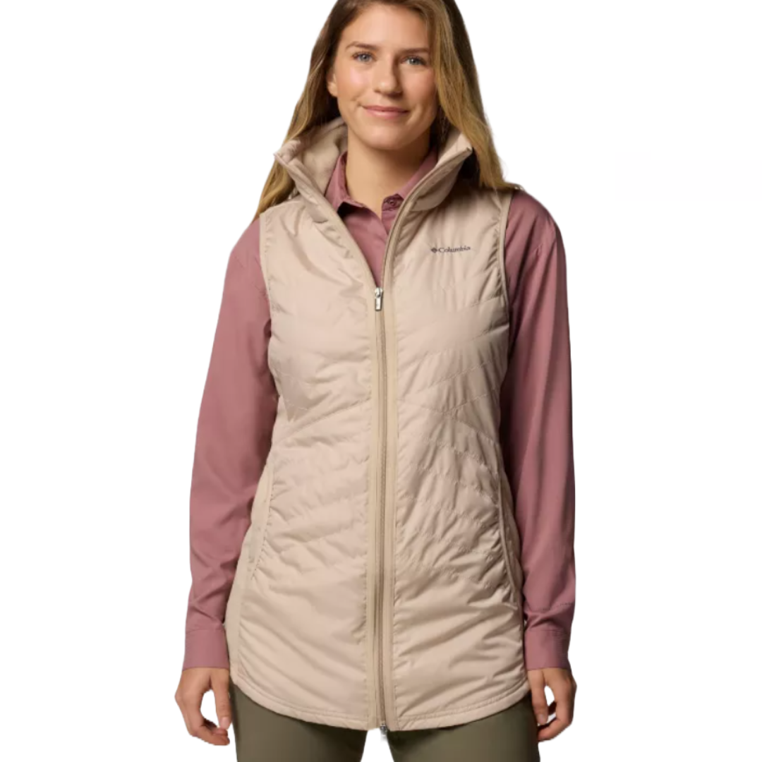 A woman wearing a beige quilted vest over a long-sleeve mauve shirt. The vest has a front zipper and stand-up collar.