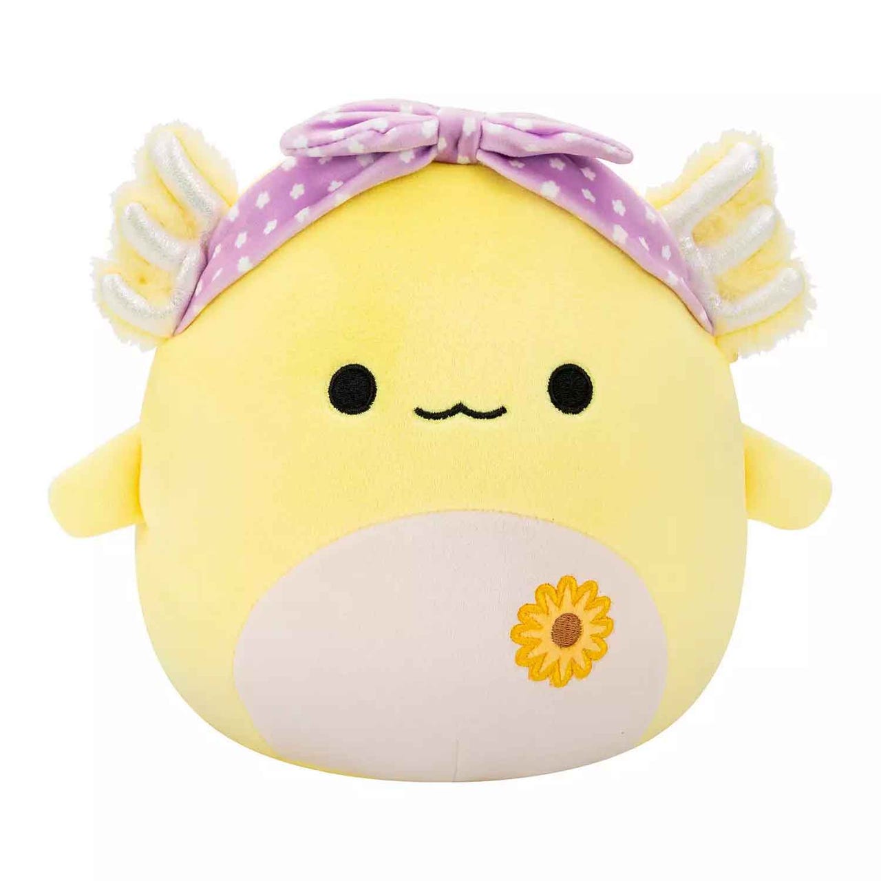 A yellow Squishmallow axolotl with a cream belly and sunflower detail, features fluffy gills, a simple smiley face, and wears a purple polka-dotted bow on its head.