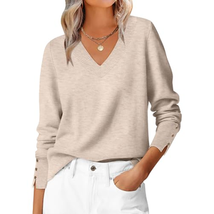 A beige V-neck sweater with buttoned cuffs is paired with white pants. The outfit is accessorized with a necklace featuring a round pendant.