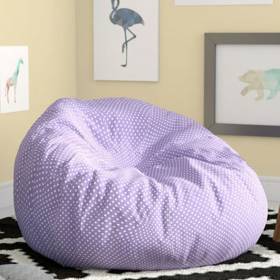 A purple polka dot bean bag chair sits on a black and white patterned rug in a room with framed animal art on the walls.