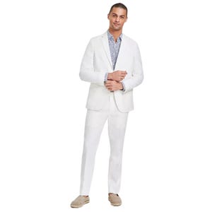 Man wearing a white suit with a printed blue shirt and espadrille shoes.