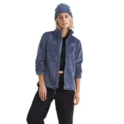 A person wearing a blue fleece jacket, black cropped pants, beanie, white socks, and gray sneakers.