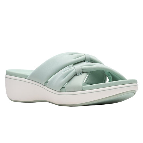 A light green slip-on sandal features a knotted cross-strap design, with a comfortable cushioned sole and a low wedge heel.