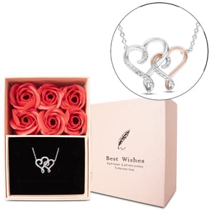 A delicate necklace features intertwined silver and rose gold hearts adorned with small diamonds, paired with a gift box containing six vibrant red faux roses and the words \“Best Wishes.\“