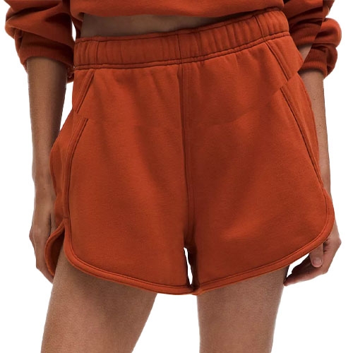 Women's rust-colored fleece shorts with an elastic waistband and side pockets, featuring a casual sporty design.