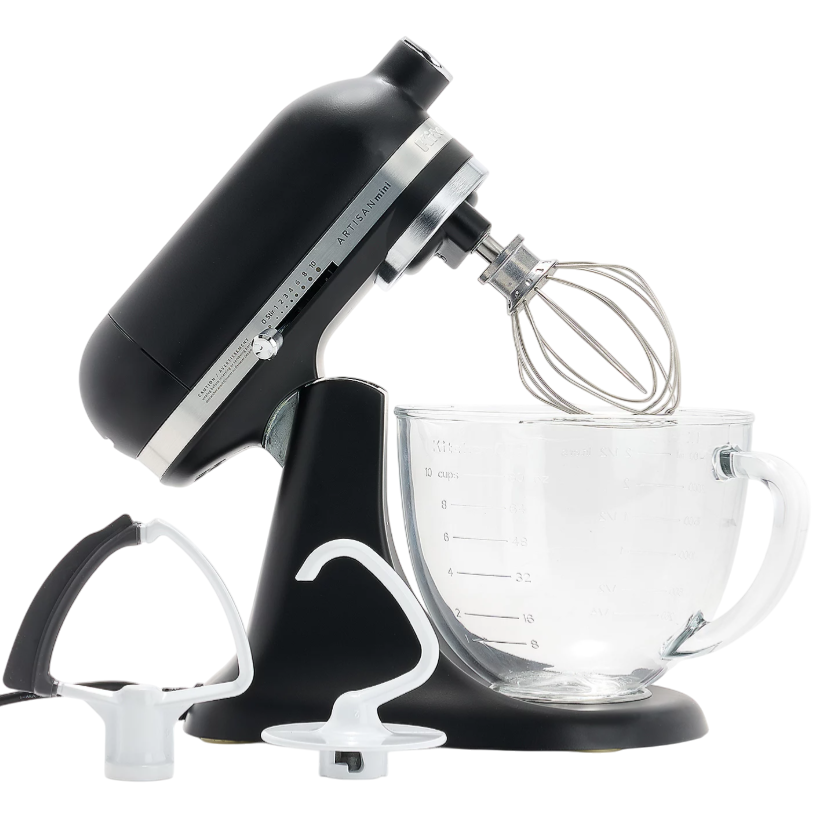 Black stand mixer with whisk attachment, accompanied by a dough hook and flat beater, and a glass mixing bowl with measurement marks.