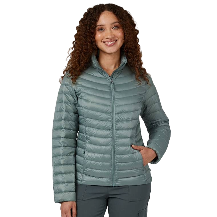 A woman wearing a 32 Degrees Packable Down Jacket in a light teal color. The jacket features a lightweight design with horizontal quilting, a front zipper closure, and two side pockets, suitable for casual and outdoor wear.