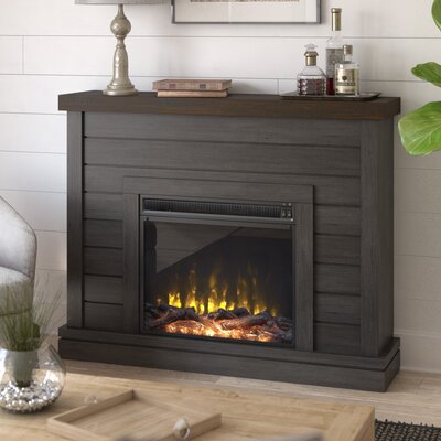A 47\“ electric fireplace with a dark gray wooden mantel surrounds a glass-front enclosure displaying realistic orange flames over what mimic the look of burning logs.