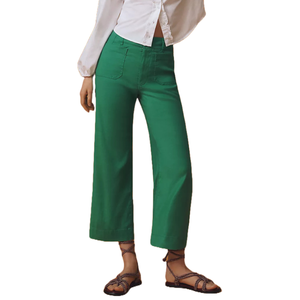 Green cropped wide-leg pants paired with a white button-up shirt and black strappy sandals.
