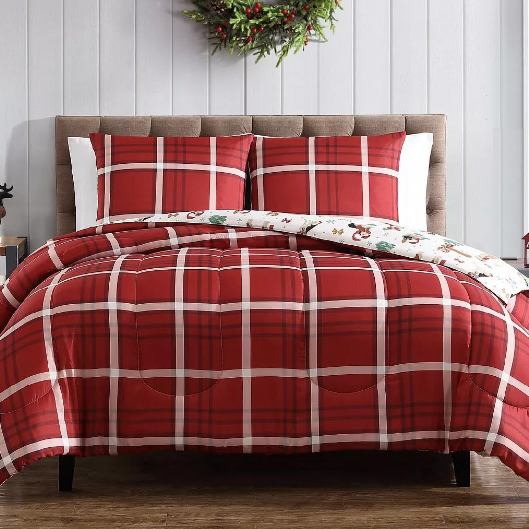 A red and white plaid comforter set on a bed, with matching pillowcases and a decorative holiday-themed sheet.