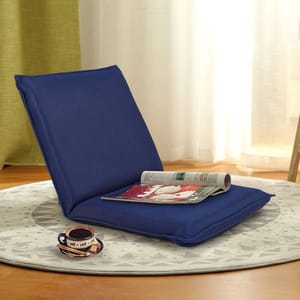 A blue adjustable recliner floor chair with a cushioned seat and backrest is set on a patterned round rug. It has a magazine on the seat and a cup of coffee placed on the floor next to it.
