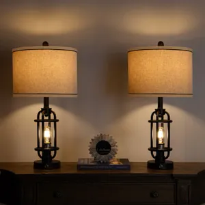 Two table lamps with cylindrical shades and industrial-style bases, turned on and illuminating a wall.