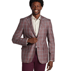 A man wearing a plaid blazer over a light-colored dress shirt, paired with dark maroon pants, poses with a slight smile against a plain backdrop.