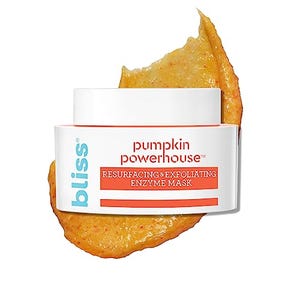 A jar of Bliss Pumpkin Powerhouse Resurfacing & Exfoliating Enzyme Mask sits on a backdrop of its contents, a textured orange paste.
