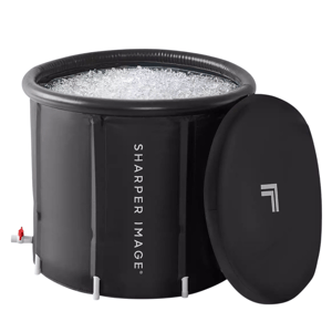 A cylindrical black ice bath with the \“Sharper Image\“ logo, filled with ice, includes a removable lid.