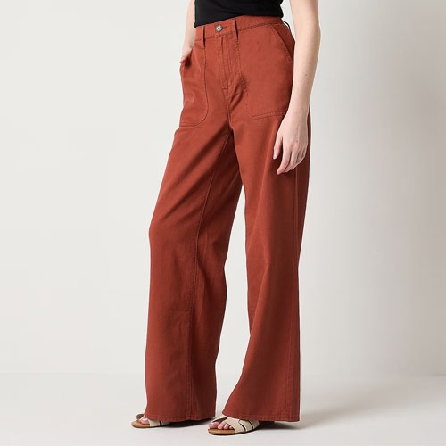 A person is wearing rust-colored wide-leg pants and black open-toe sandals.