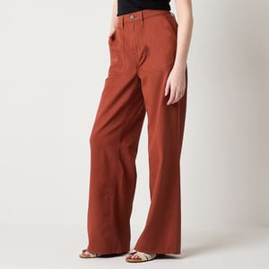 A person is wearing rust-colored wide-leg pants and black open-toe sandals.