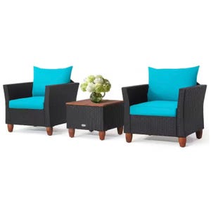 3-piece Costway Patio Set includes two black wicker armchairs with bright blue cushions and a square side table, featuring wooden legs and a vase of white flowers.