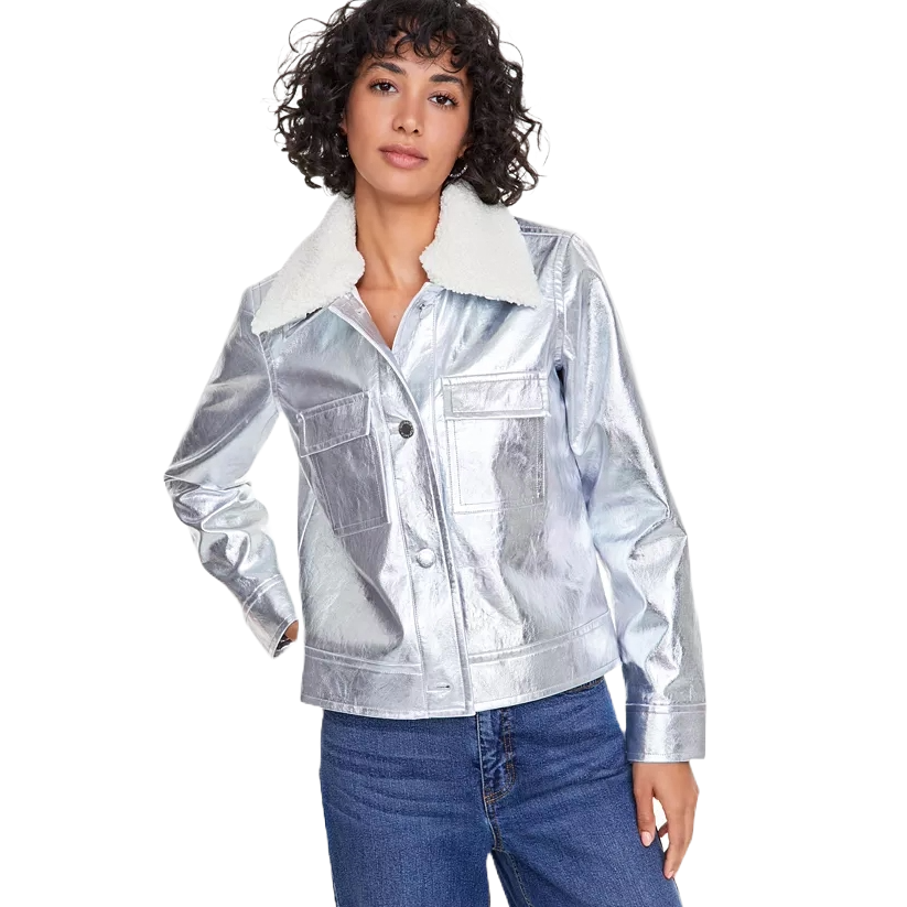 The metallic faux-leather jacket is a shiny silver color with a white sherpa collar, featuring a button-up front with two chest pockets. It has long sleeves and is paired with blue jeans.