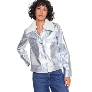 The metallic faux-leather jacket is a shiny silver color with a white sherpa collar, featuring a button-up front with two chest pockets. It has long sleeves and is paired with blue jeans.