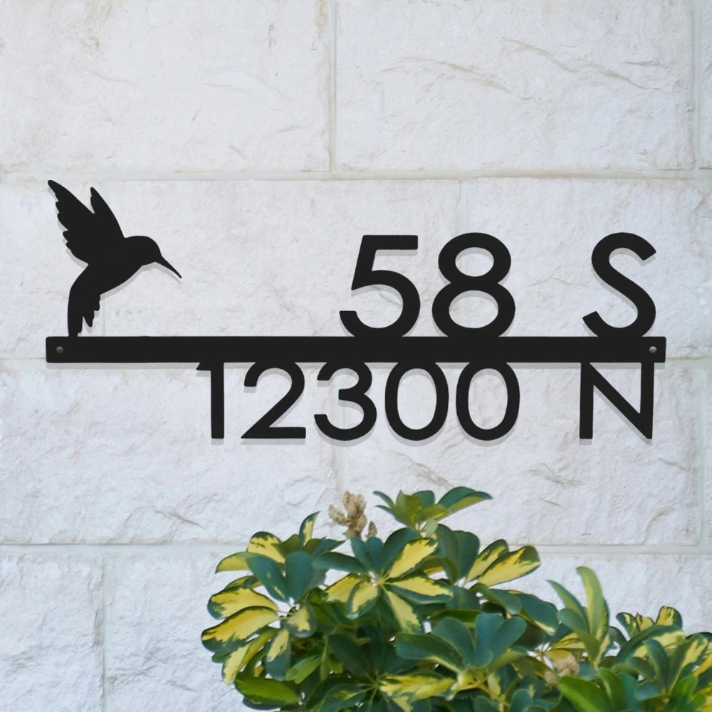 A decorative metal address sign features a hummingbird silhouette with the numbers \“58 S\“ and \“12300 N\“ on a light stone wall background.