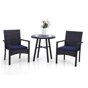 A 3-piece patio bistro set featuring two rattan-style armchairs with navy cushions and a round, black metal table. The table has a vase with flowers and two cups on it.