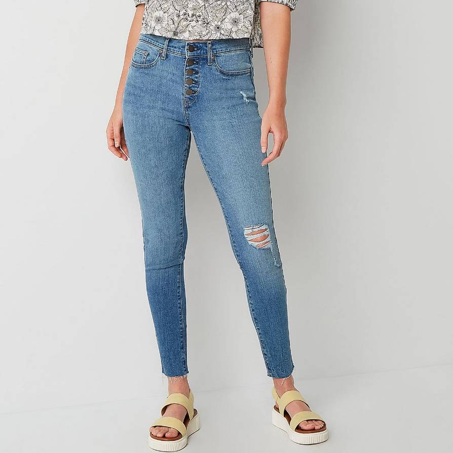 Blue high-waisted skinny jeans with lace-up detail and distressed knees, paired with two-tone platform sandals.