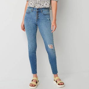 Blue high-waisted skinny jeans with lace-up detail and distressed knees, paired with two-tone platform sandals.