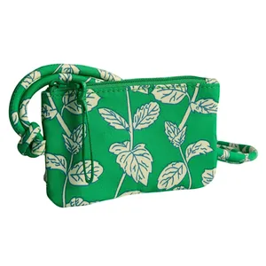 Green pouch with a leaf pattern and a knotted strap, featuring a zipper closure.