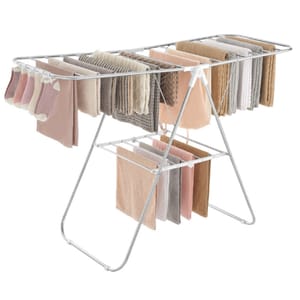 A metal clothes drying rack with multiple bars holds various pastel-colored garments, including socks, towels, and shirts, arranged neatly for drying.