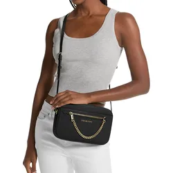 A person is wearing a grey sleeveless top and white pants, holding a black crossbody bag with gold chain and zipper accents.