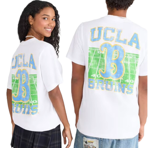 Two people wearing white T-shirts featuring a UCLA Bruins design with a large \“B\“ and a football field graphic on the back.