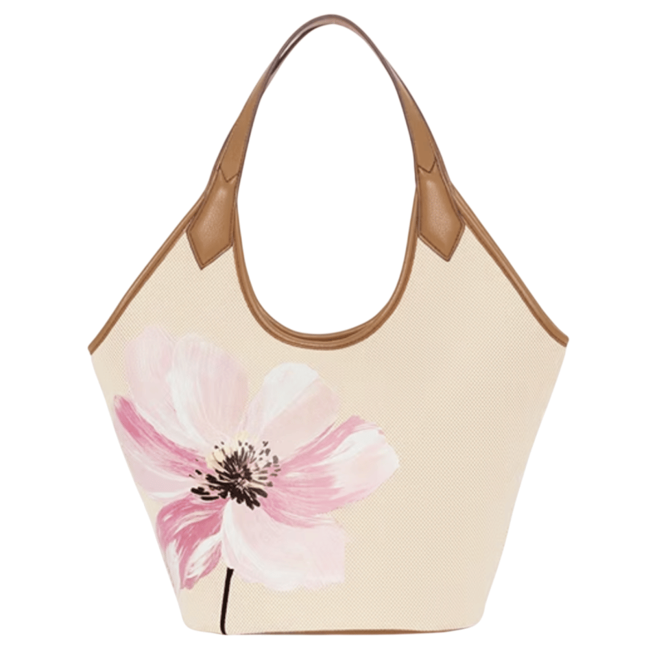 A beige tote bag with brown leather handles and a large pink floral design on the front.