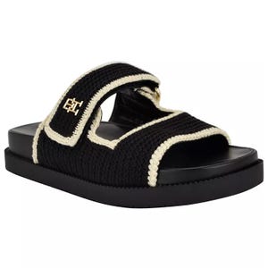 Tommy Hilfiger Women's Crochet Sandals feature a black crochet design with cream edging, a wide adjustable strap, and a comfortable flat sole. A small gold logo embellishes the strap.