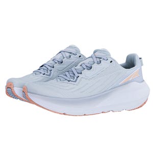 Light blue athletic running shoes with a streamlined design, featuring a cushioned white midsole and subtle peach accents on the outsole and brand logo.