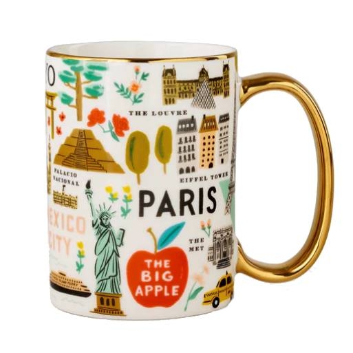 The Bon Voyage Mug features colorful illustrations of iconic landmarks such as the Eiffel Tower, the Louvre in Paris, the Statue of Liberty and the Met in New York City, and the Palacio Nacional in Mexico City, with a gold handle for added elegance.