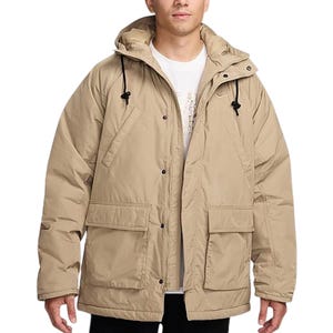 A beige Nike parka jacket with a hood, featuring drawstrings and large front pockets. It's designed for warmth and comfort, with button and zipper closure.