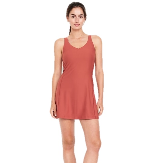 A woman is wearing a sleeveless, rust-colored dress with a V-neckline. The dress has a simple, fitted design that flares slightly at the hem.