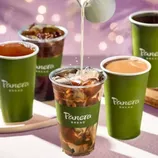 Panera Bread cups filled with various drinks, including iced beverages and coffee, feature prominently. Milk is being poured into a clear cup with ice and coffee. All cups have the Panera Bread logo.
