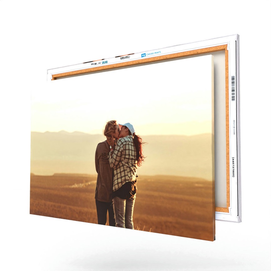 A canvas print displays two people kissing against a scenic backdrop, presented with a wooden frame edge.