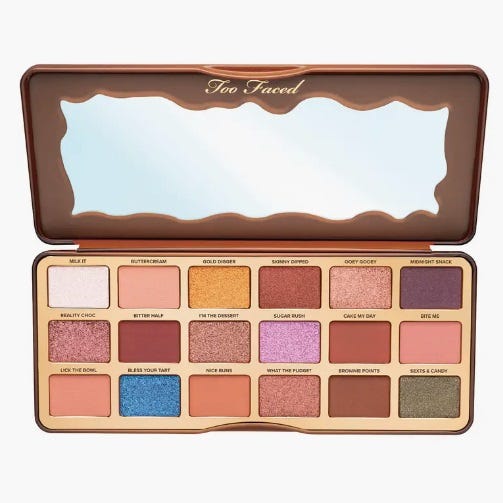 The Too Faced Better Than Chocolate Palette contains 18 eyeshadows with a mix of matte, shimmer, and glitter finishes in a range of neutral to colorful shades, housed in a chocolate bar-shaped case with a mirror.