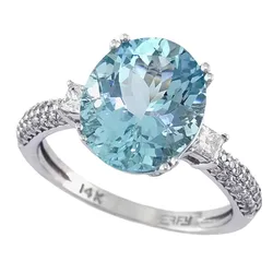 A 14K white gold ring featuring a large oval blue gemstone, possibly aquamarine, flanked by two smaller stones and a band adorned with pavé-set diamonds.