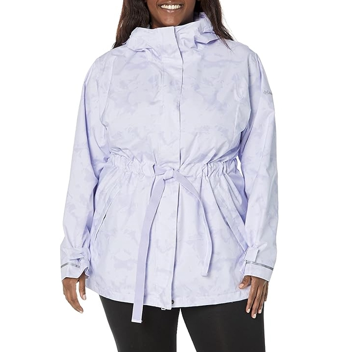 Columbia Women's Trench II Jacket in a light lavender color features an adjustable waist with a tie belt, hood, and long sleeves. It offers a clean, tailored look suitable for various weather conditions.