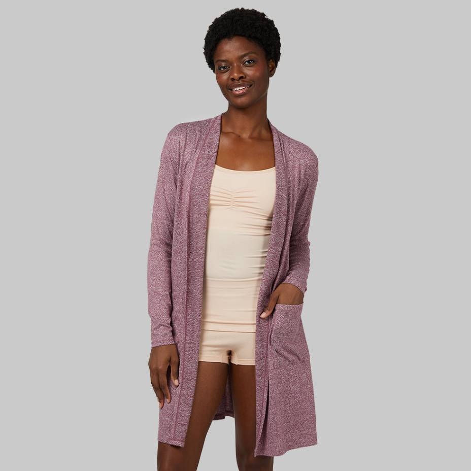 Woman wearing a long-sleeved maroon cardigan over a cream tank top and shorts.