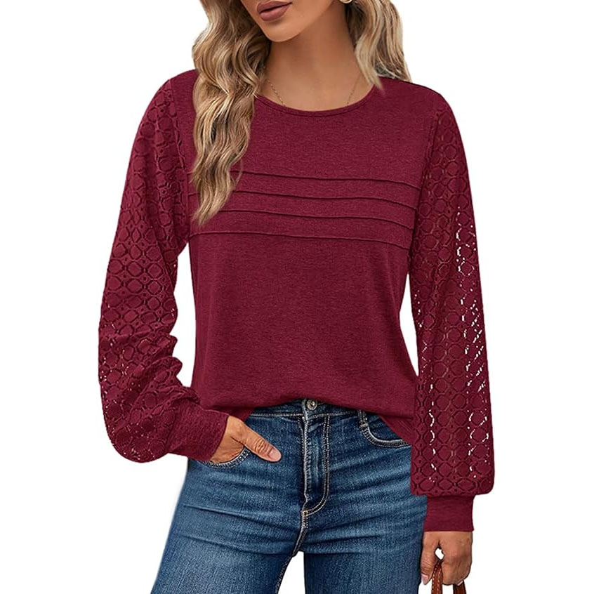 A woman wearing a long-sleeve maroon blouse with lace sleeves and pleated front details, paired with blue jeans.
