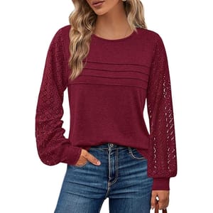 A woman wearing a long-sleeve maroon blouse with lace sleeves and pleated front details, paired with blue jeans.